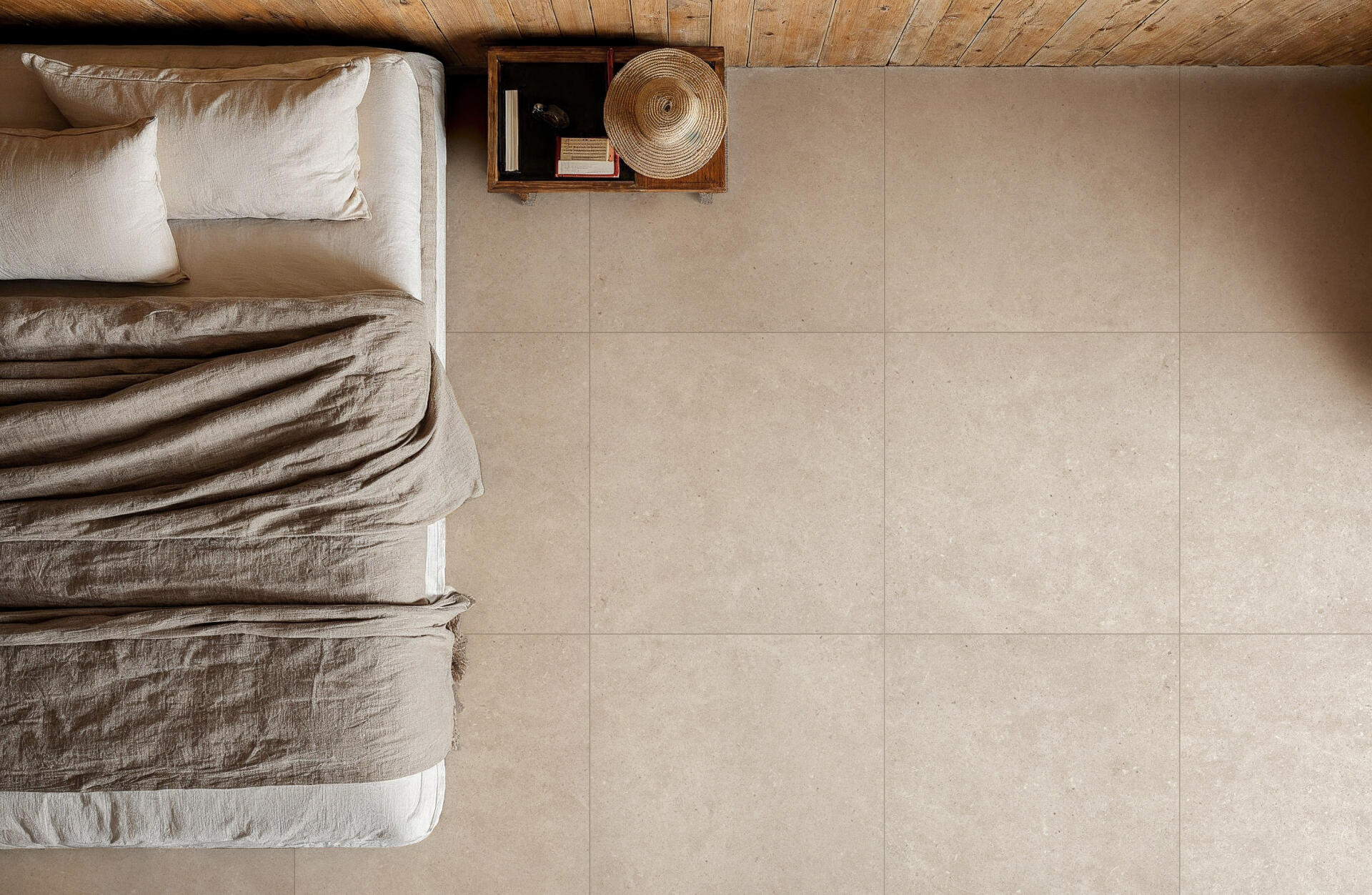 Woonkamer van boven met beige steenlooktegels, een bank en natuurlijke accessoires