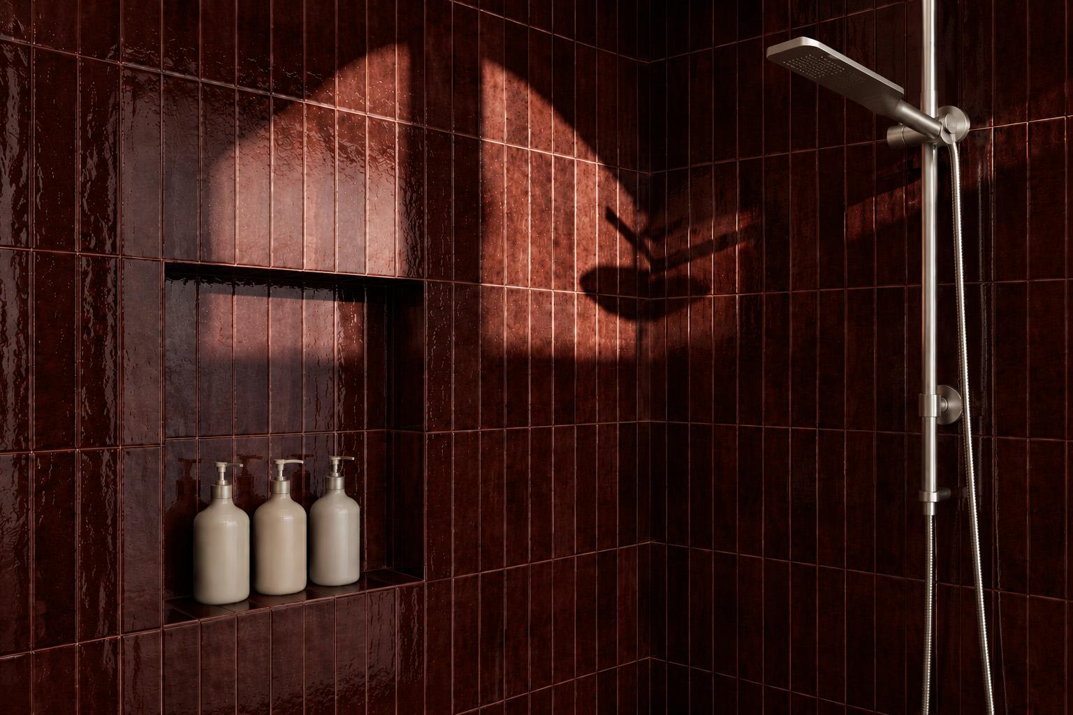 Badkamer met glanzende bordeauxrode Sottocer Earth Burgundy wandtegels, een betegelde nis en een douche